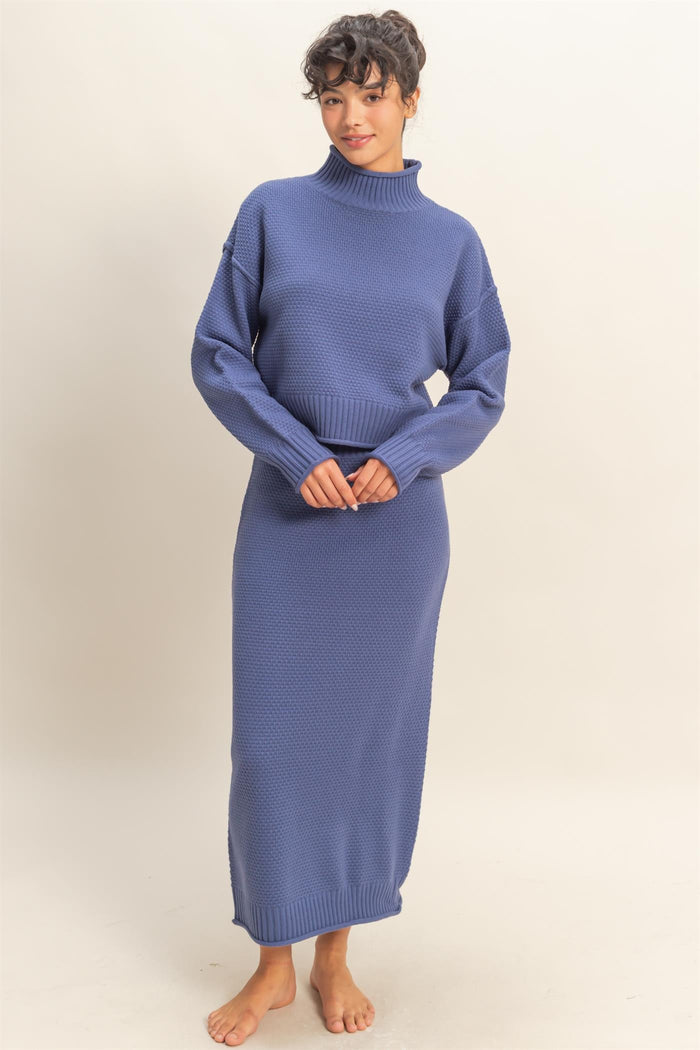 woman wearing a blue cozy knit two-piece sweater and skirt set with a high neckline and long sleeves