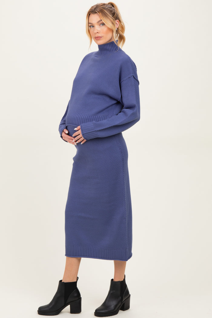 woman wearing a navy blue maternity turtleneck dress and cradling her baby bump