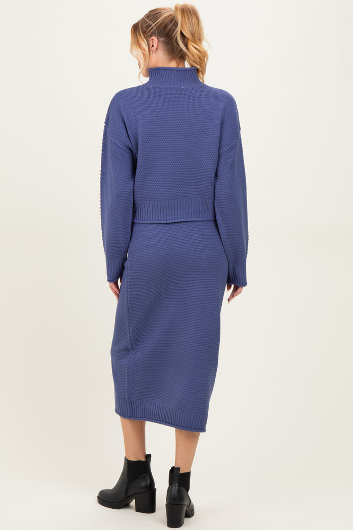 woman wearing a dark blue maternity long sweater dress with a fitted waist and ribbed knit design, viewed from the back