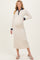woman wearing a cream long sleeve maternity dress with a navy collar and buttons, showing her baby bump