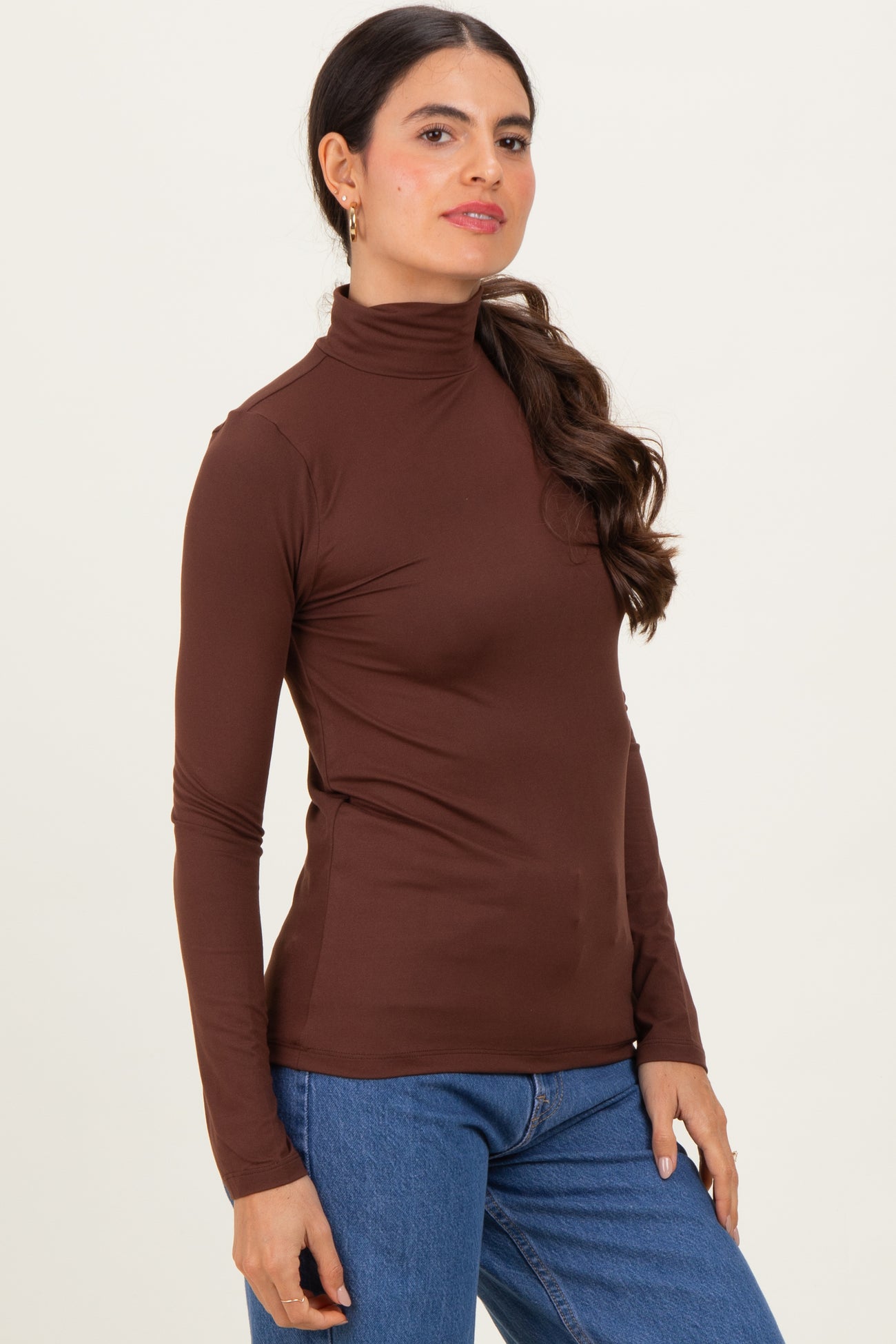 woman wearing a brown long sleeve mock neck top paired with blue jeans