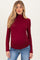 woman wearing a burgundy maternity turtleneck top and showing her baby bump with a relaxed fit and long sleeves