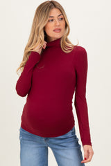 woman wearing a burgundy long sleeve maternity top with a fitted style and baby bump visible