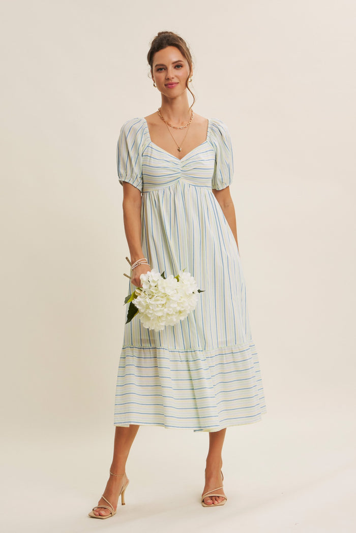 woman wearing a white striped midi dress with puff sleeves and a square neckline, holding a bouquet of flowers