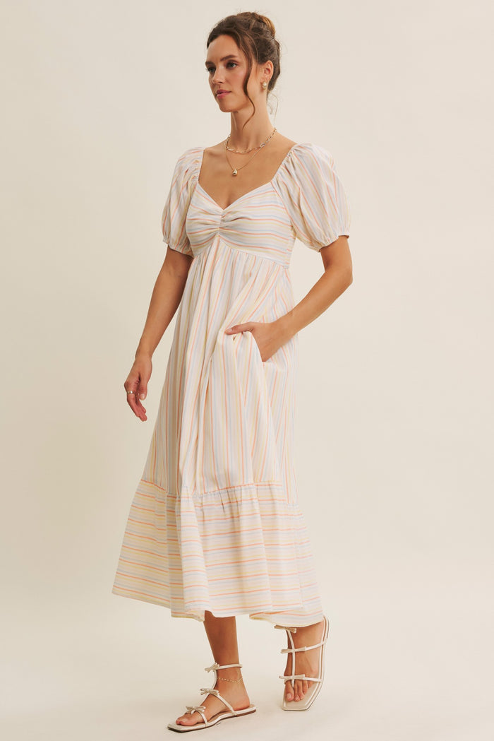 woman wearing a striped midi dress with puff sleeves and a sweetheart neckline, featuring side pockets and a tiered hemline