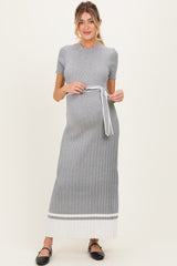 woman wearing a grey ribbed maternity dress with a white tie belt and a baby bump visible