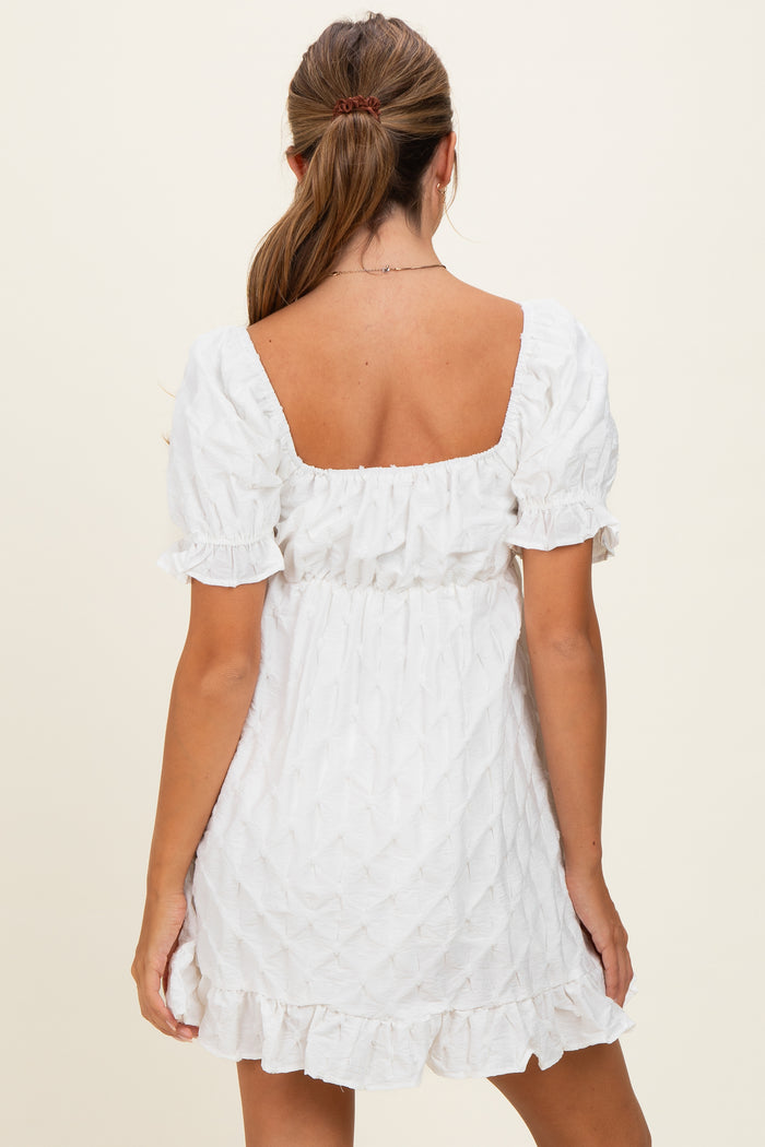 woman wearing a white short puff sleeve dress with a square back and ruffled hem