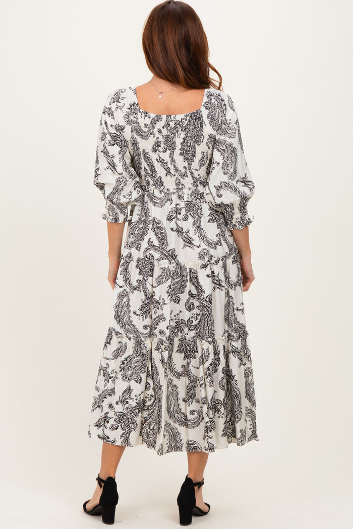 woman wearing a black and white patterned midi dress with puff sleeves and a tiered skirt