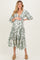 woman wearing a green and white floral print maternity dress with puff sleeves and a baby bump