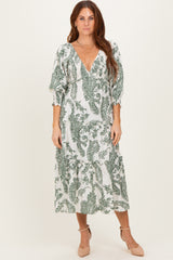 woman wearing a green and white paisley print midi dress with a deep v-neckline and puff sleeves