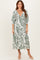woman wearing a green and white paisley print midi dress with a deep v-neckline and puff sleeves