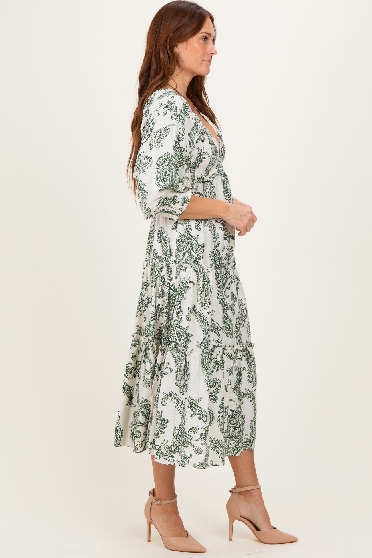 woman wearing a white and green floral print midi dress with three-quarter sleeves and a flowy skirt