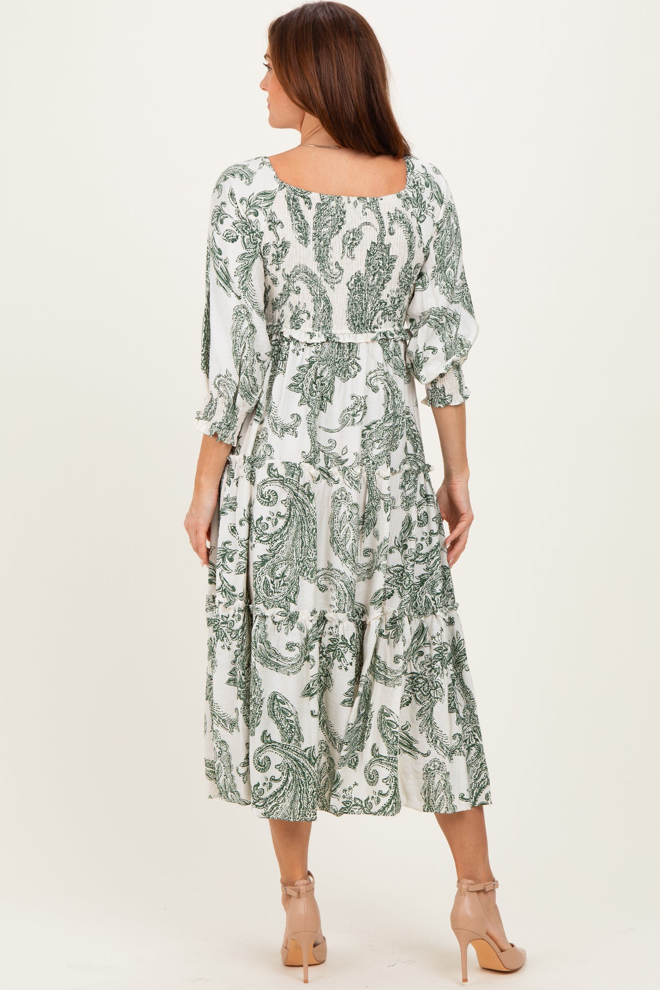 woman wearing a green and white floral print midi dress with puff sleeves and a tiered skirt, seen from the back