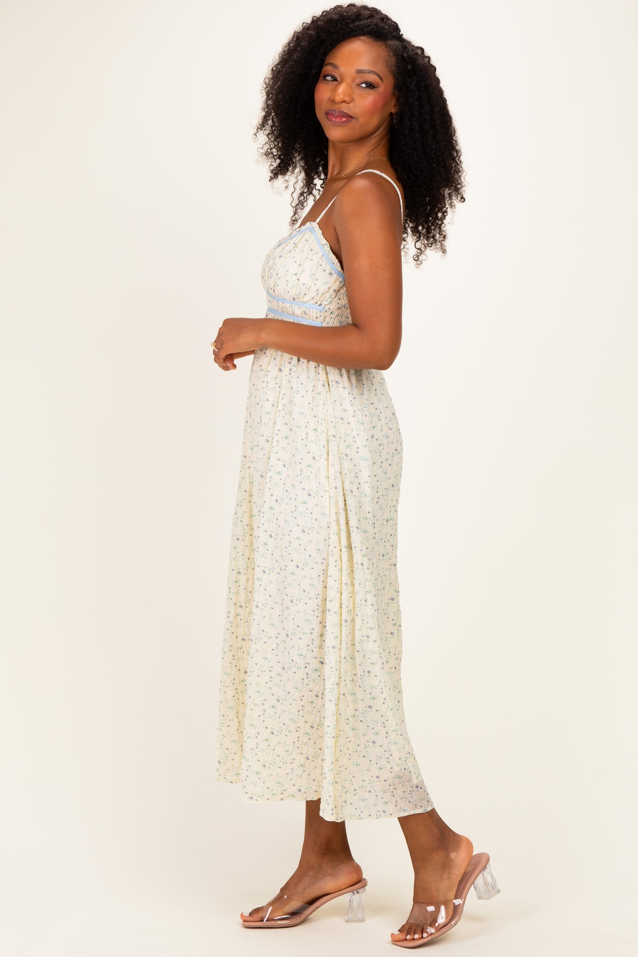 woman wearing a floral midi dress with adjustable spaghetti straps and a flowy skirt, smiling to the side
