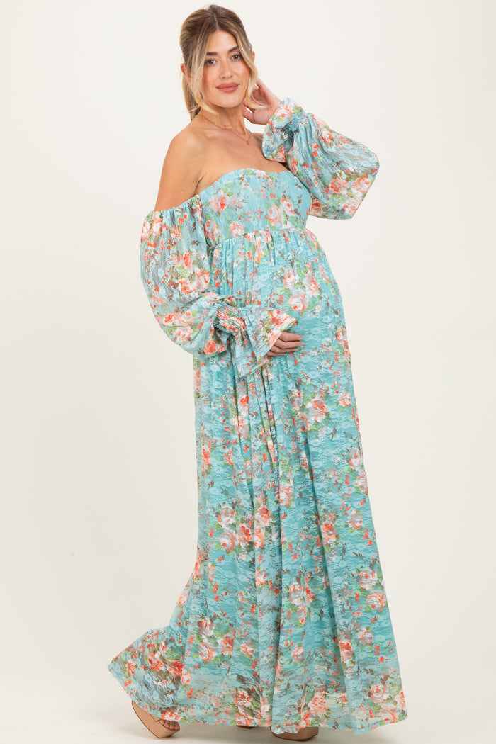 woman wearing a blue floral off-the-shoulder maternity dress, showcasing her baby bump