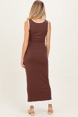 woman wearing a brown maternity maxi dress with a white ruffled hem, showing her baby bump from the back