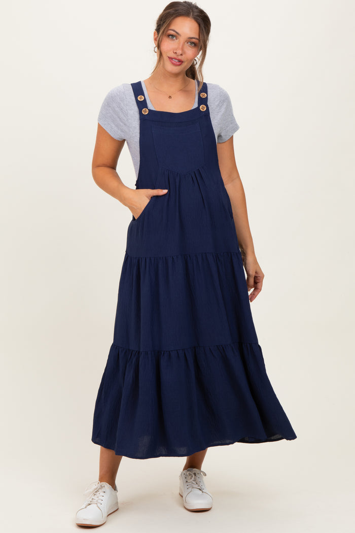 woman wearing a navy blue tiered maternity dress with button details and pockets, styled with a gray t-shirt underneath
