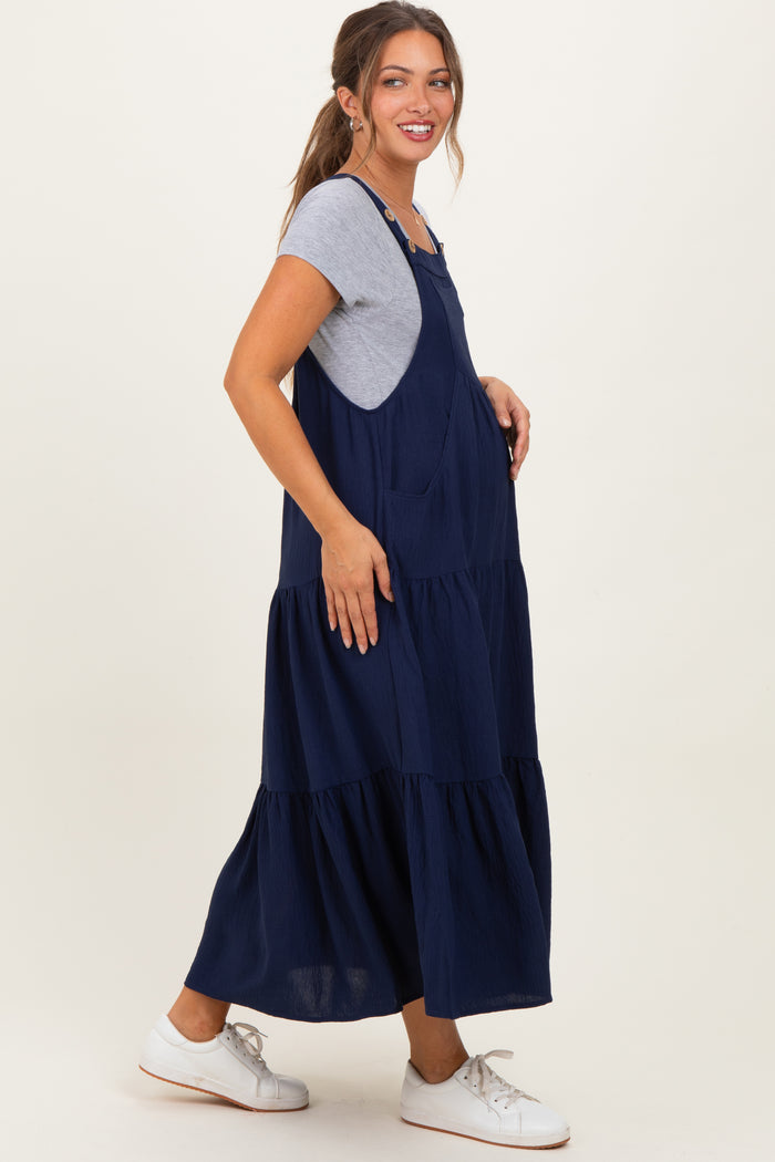 woman wearing a navy blue tiered maternity dress over a gray short sleeve top, styled with white sneakers