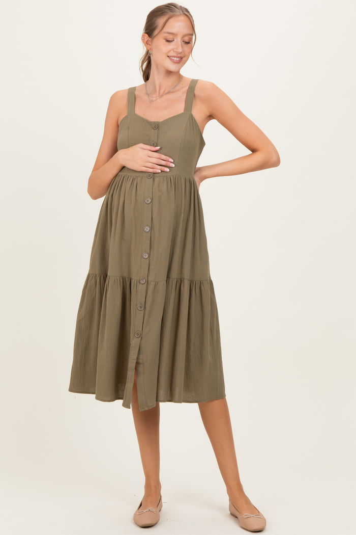 woman wearing an olive green maternity button-up dress with a tiered skirt and holding her baby bump