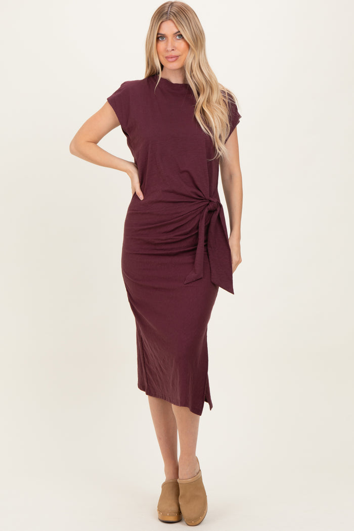 woman wearing a burgundy short sleeve wrap dress with a side tie detail and a midi length