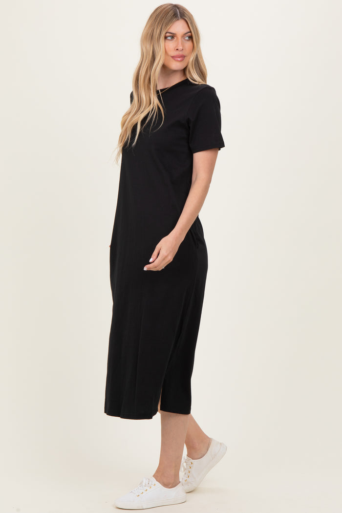 woman wearing a black midi t-shirt dress with side pockets and short sleeves, styled with white sneakers