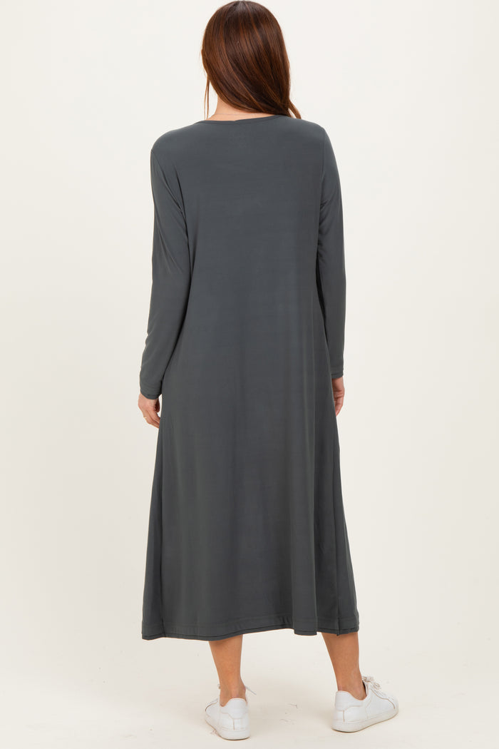 woman wearing a long sleeve dark gray maxi dress, standing with her back to the camera