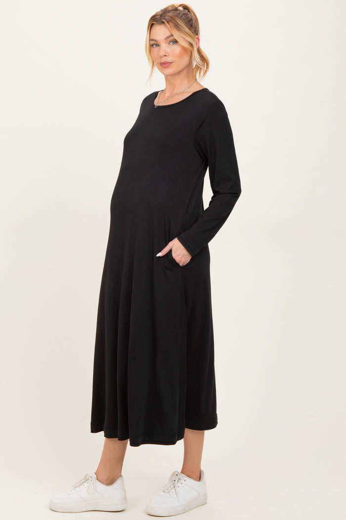 woman wearing a black long sleeve maternity dress with pockets and a visible baby bump