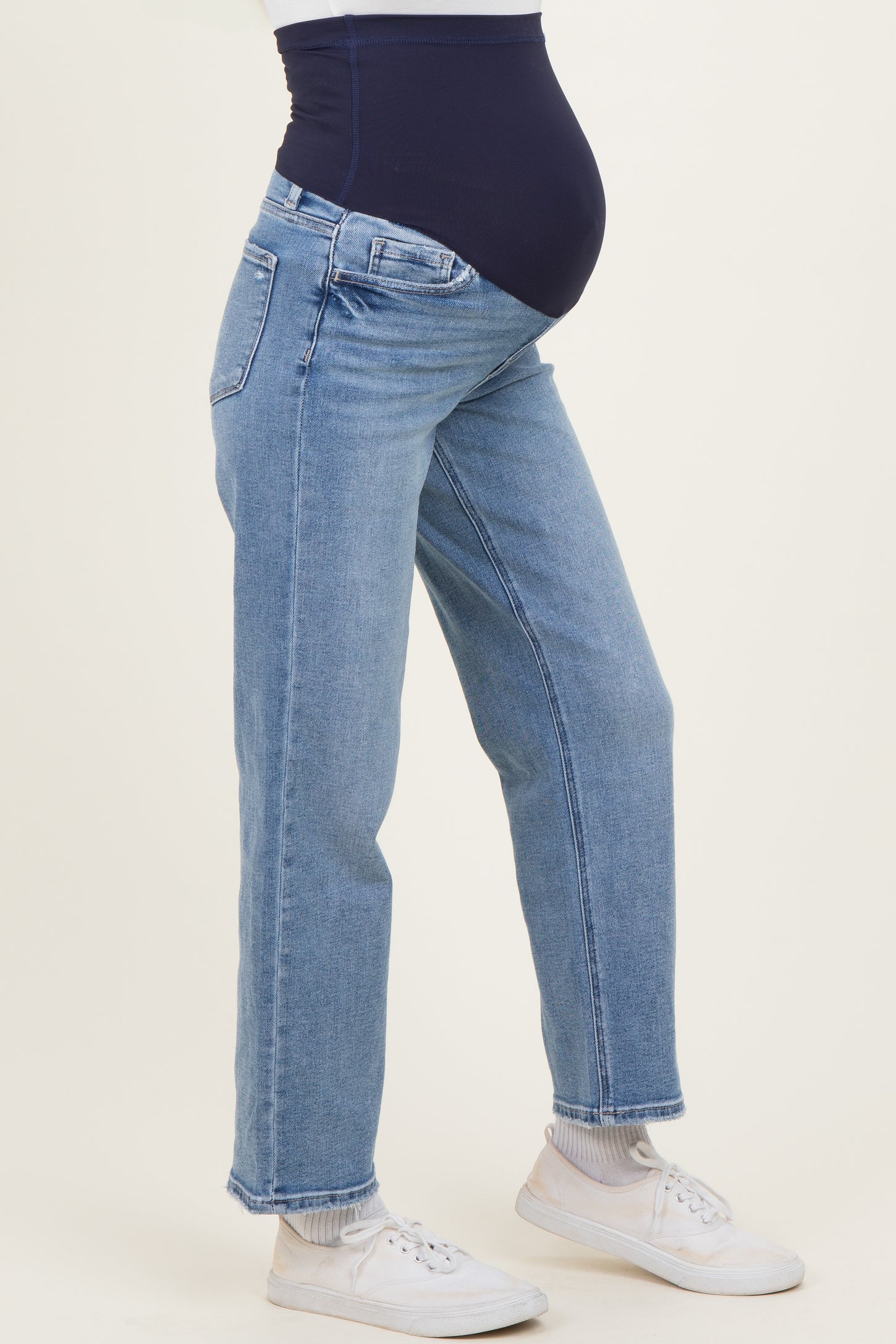 woman wearing light blue maternity jeans with a navy waistband and a visible baby bump