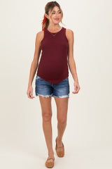 woman wearing a burgundy maternity tank top and denim shorts, showing her baby bump while walking