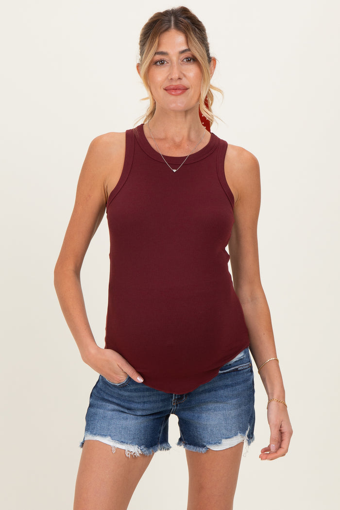 woman wearing a burgundy ribbed maternity tank top and denim shorts with a visible baby bump