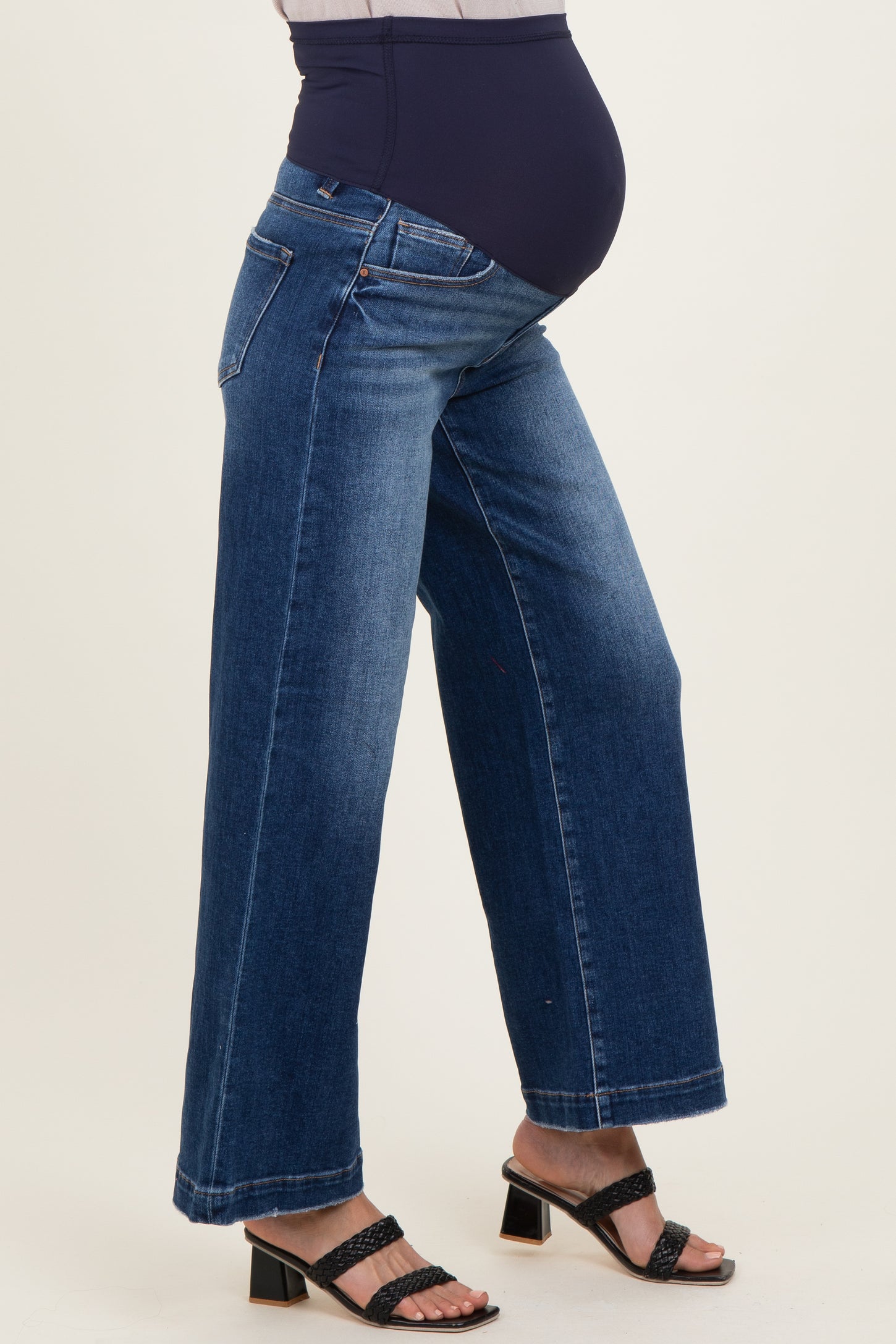 woman wearing high-waisted blue maternity wide-leg jeans with a supportive belly band and chunky heeled sandals