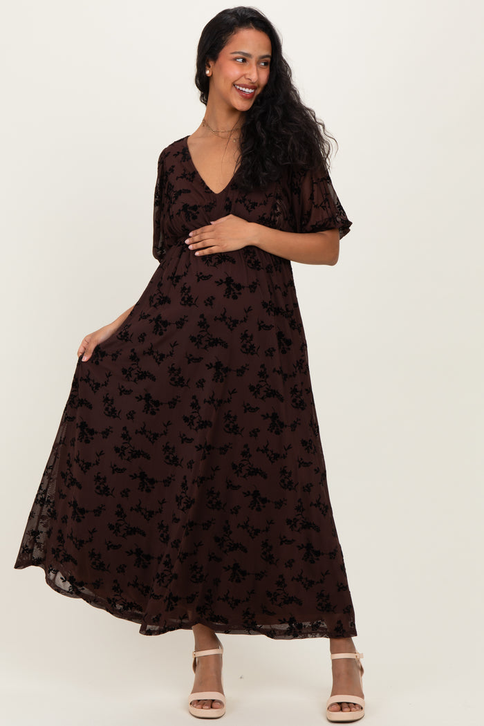 woman wearing a brown floral maternity maxi dress with short sleeves and a v-neckline, showcasing her baby bump