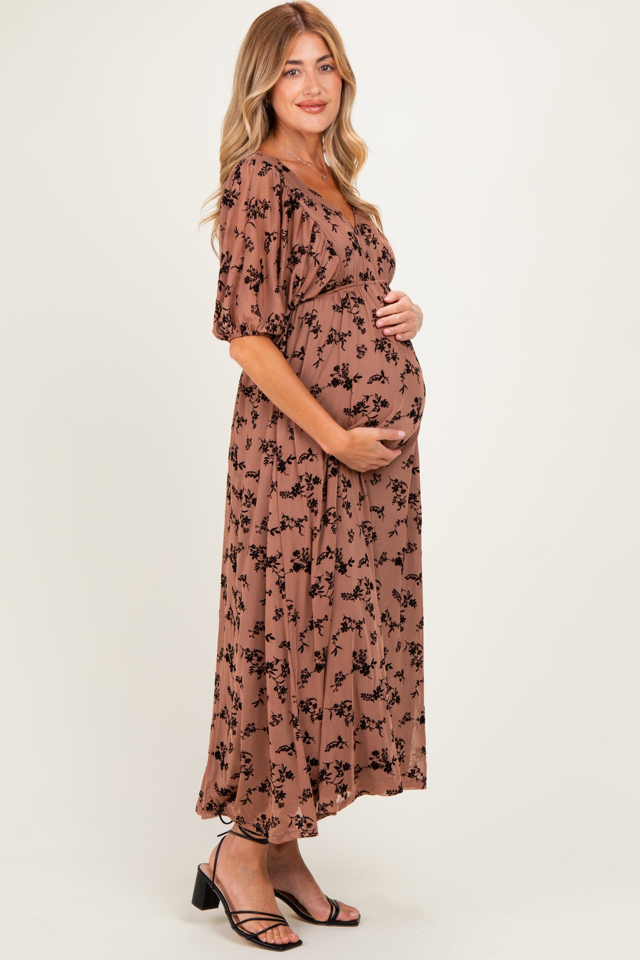 woman wearing a brown floral maternity maxi dress and holding her baby bump