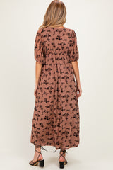 woman wearing a brown floral print maternity maxi dress with puff sleeves, view from the back