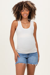 woman wearing a light gray maternity tank top and denim shorts with a visible baby bump