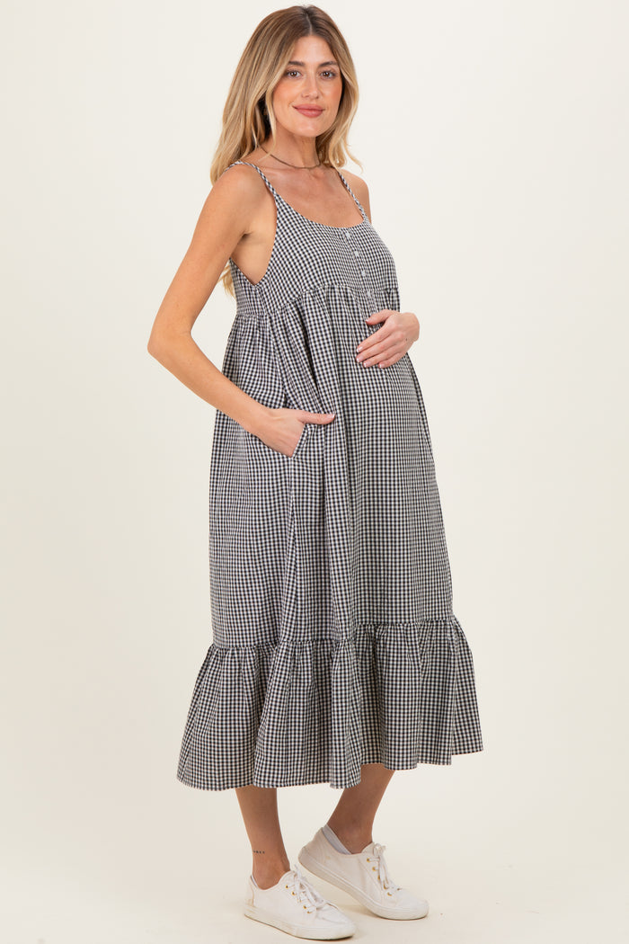 woman wearing a black and white gingham maternity dress with pockets and a tiered hem, showing her baby bump