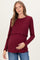 woman wearing a burgundy maternity top with ribbed texture and ruffled hem, holding her baby bump