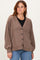 woman wearing a brown checkered cardigan with a deep v-neck and buttons, paired with a black top and blue jeans