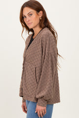 woman wearing a brown textured button-up cardigan with oversized sleeves and front pockets