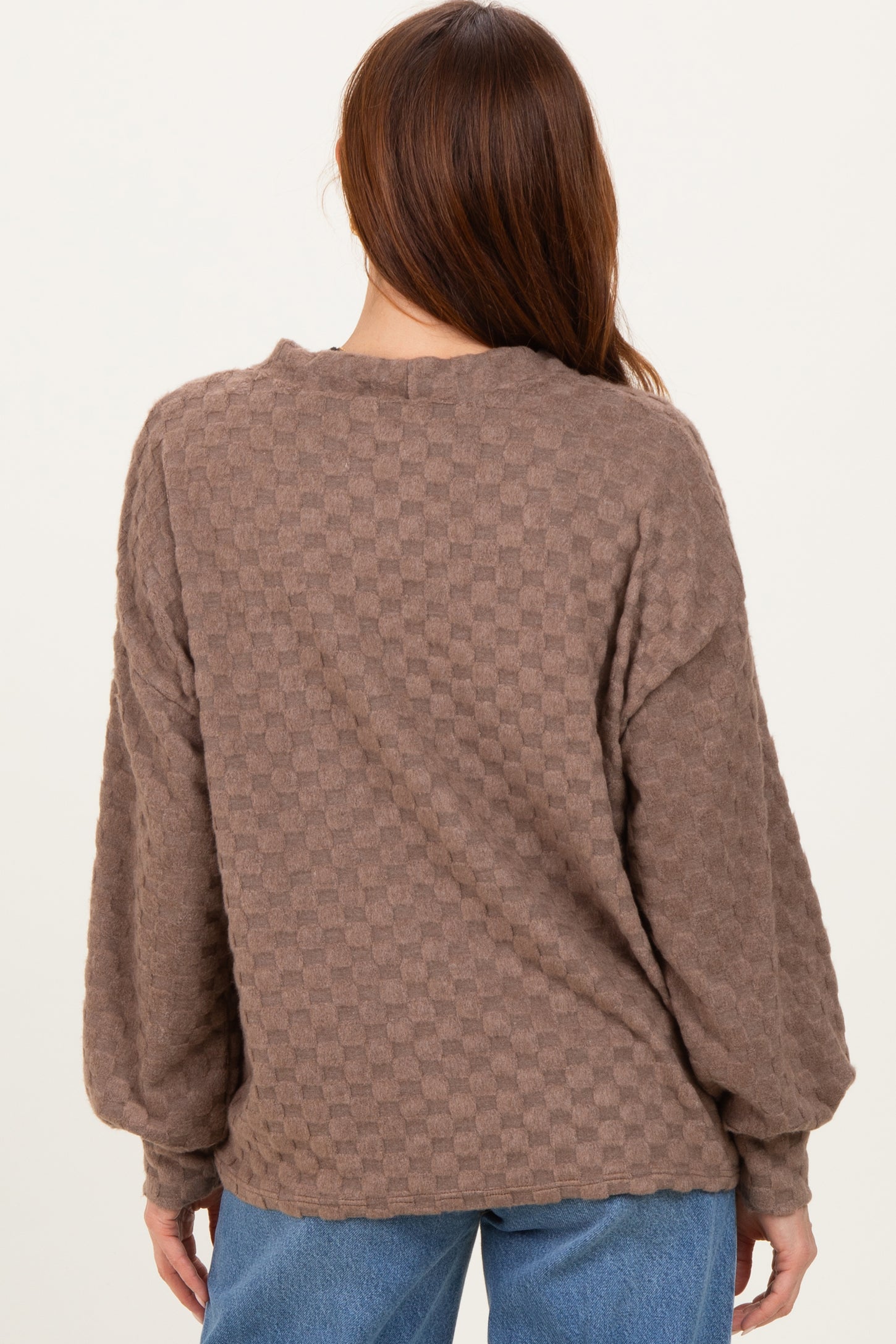woman wearing a brown checkered oversized sweater with long sleeves, view from the back