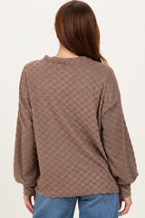 woman wearing a brown checkered oversized sweater with long sleeves, view from the back