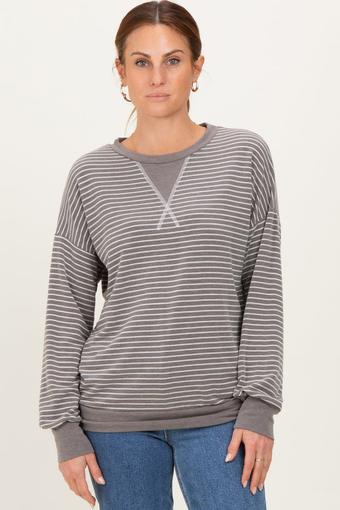 woman wearing a gray striped long sleeve sweatshirt with a relaxed fit and ribbed cuffs paired with blue jeans
