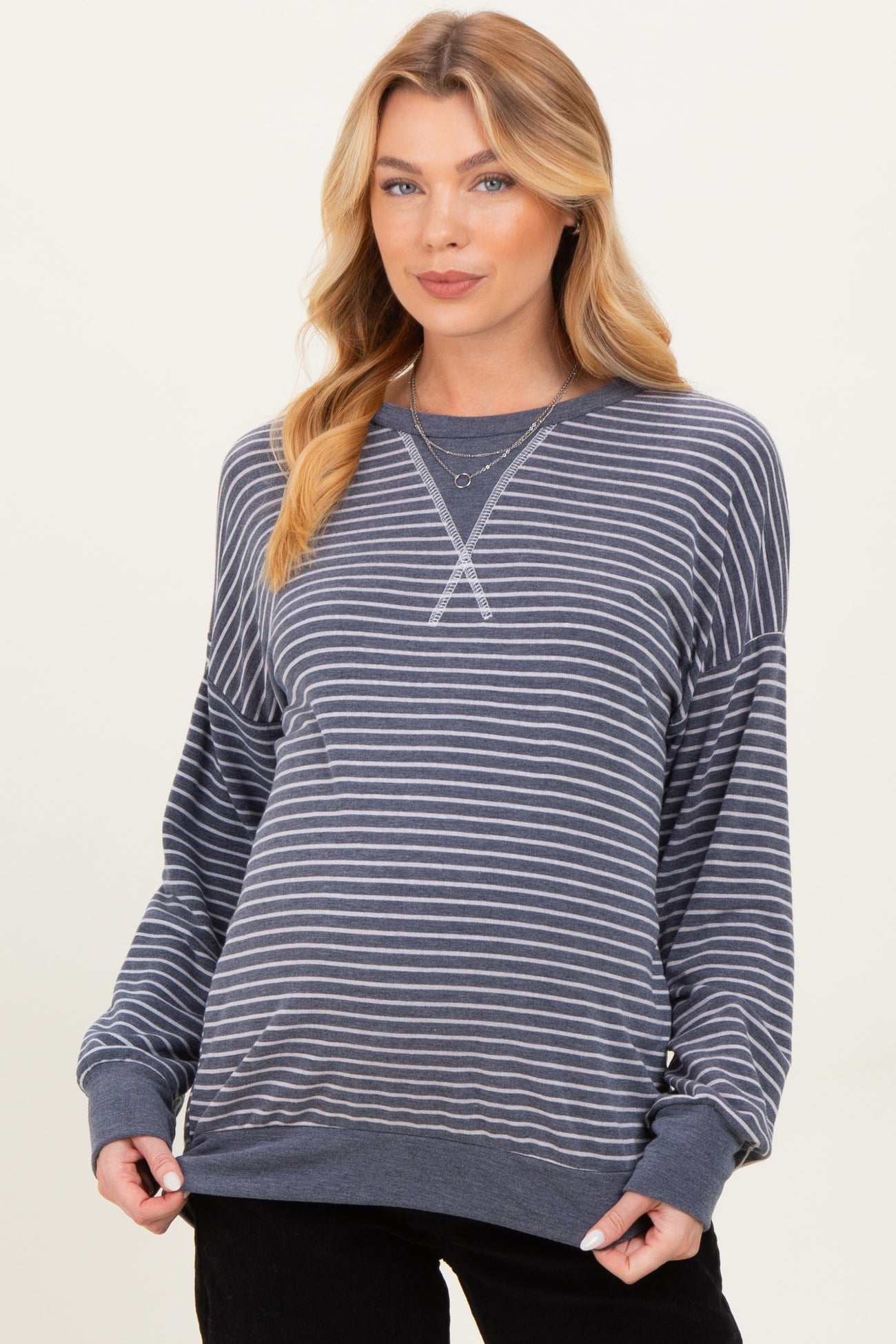 woman wearing a navy and white striped maternity sweatshirt with a relaxed fit and long sleeves, showing her baby bump