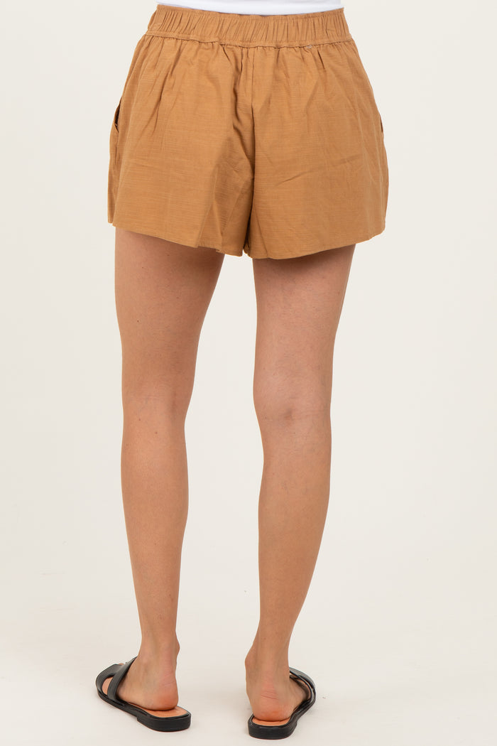 woman wearing tan high-waisted shorts with an elastic waistband and side pockets, viewed from the back