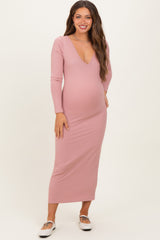 woman wearing a light pink ribbed long sleeve maternity dress with a v-neck and a visible baby bump