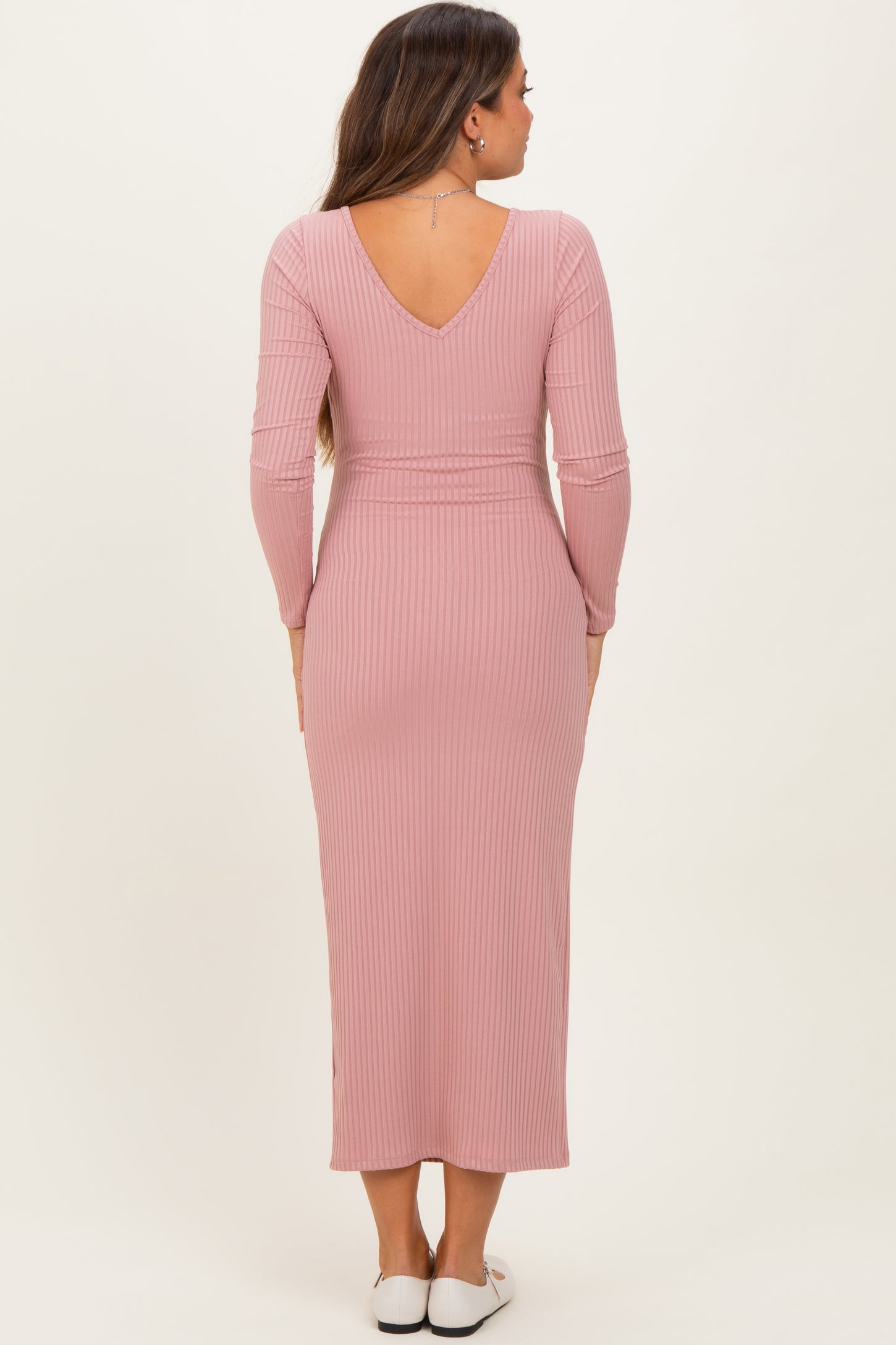 woman wearing a mauve ribbed maternity dress with long sleeves and a V-back design