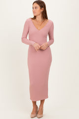 woman wearing a light pink ribbed long sleeve midi dress with a deep v-neckline and side-slit detailing