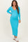 woman wearing a bright blue long sleeve maternity dress with a v-neckline and holding her baby bump
