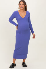 woman wearing a purple ribbed maternity dress with a deep V-neck and long sleeves, showing her baby bump
