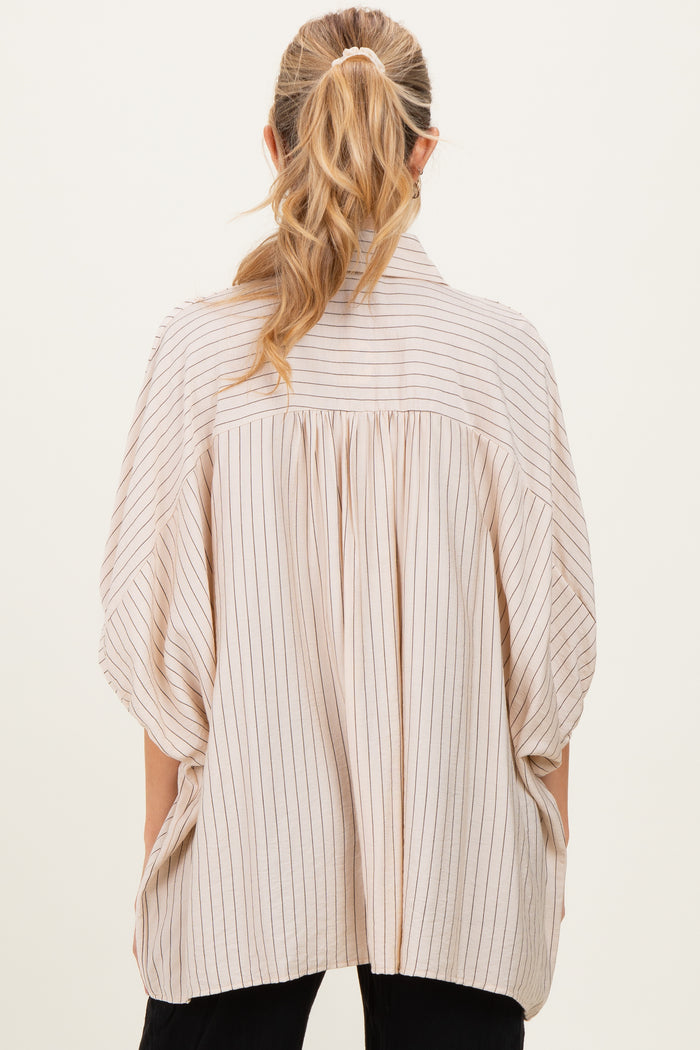 woman wearing a light beige maternity top with vertical stripes and a loose, oversized fit seen from the back